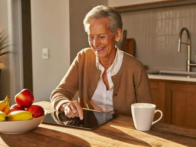 Illustrazione: una nonna ride in cucina davanti a un tablet appoggiato a una fruttiera.